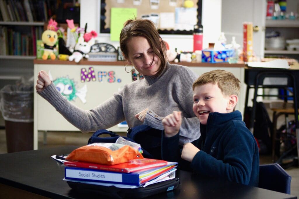 Teacher and student smiling in classroom.