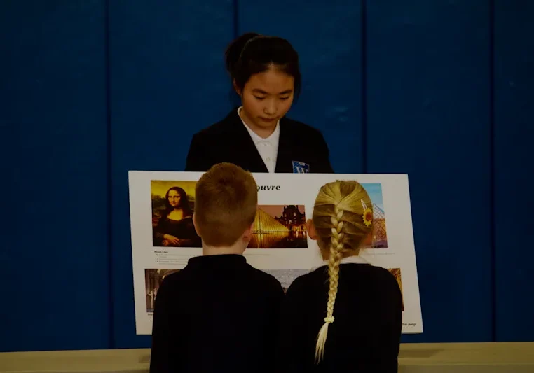 Older student presenting art poster to classmates